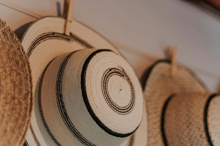 Close-up of creatively designed handmade straw hats with intricate patterns hanging indoors.