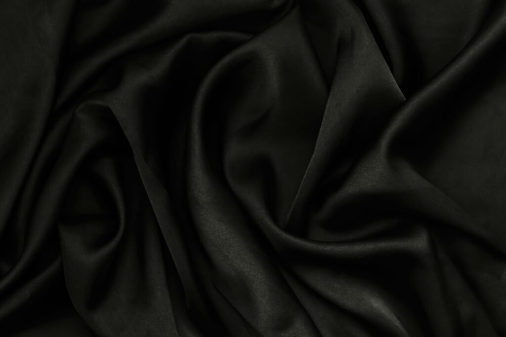 A close-up of smooth black fabric with rippling texture, perfect for background use.